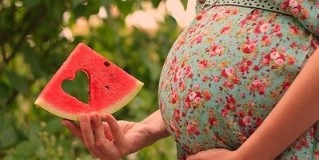 watermelon slices in the hands of pregnant woman